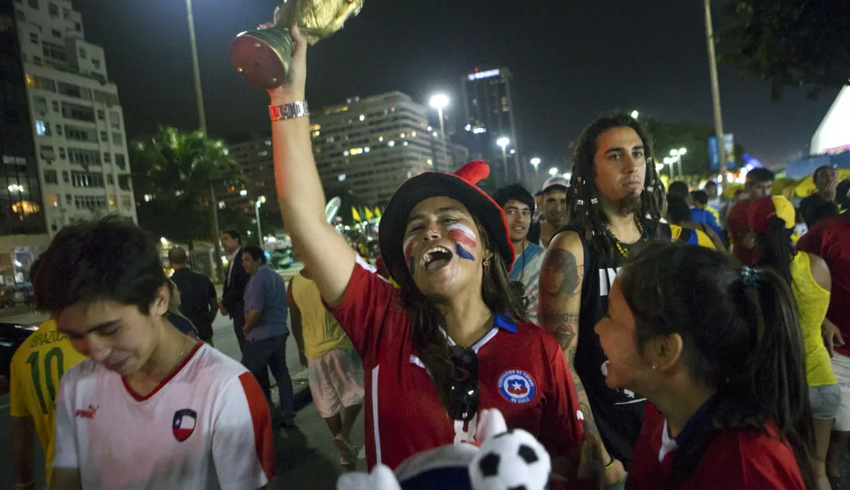 Sambil mengangkat replika trofi Piala Dunia, suporter Chili bersorak gembira menyambut kemenangan La Roja atas Spanyol 2-0 di Rio de Janeiro, Brasil, (19/6/2014). (REUTERS/Marco Bello)
