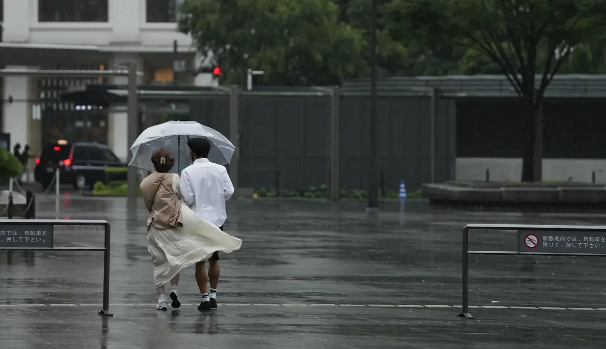 Orang-orang berjalan keluar dari stasiun kereta api Tokyo di tengah hujan, Selasa (20/9/2022). Badai tropis menumpahkan hujan lebat saat melintasi Jepang, dan bergerak ke Samudra Pasifik pada hari Selasa. (AP Photo/Hiro Komae)