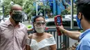 Pasangan mengenakan masker diperiksa suhu tubuhnya dalam "pernikahan massal bermasker" di sebuah taman di Filipina (15/12/2020). Pemerintah Filipina telah memberlakukan kebijakan untuk penggunaan masker di tengah kekhawatiran lonjakan kasus COVID-19 selama musim liburan. (Xinhua/Rouelle Umali)