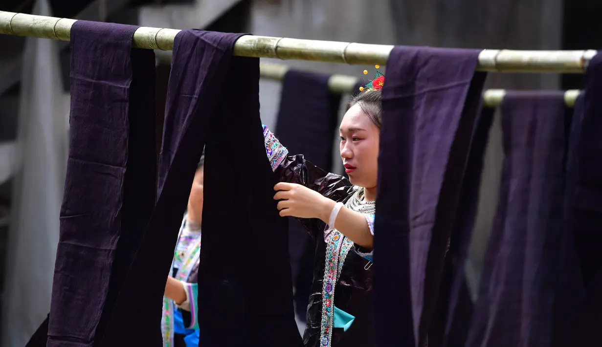 Seorang wanita menjemur kain dalam festival "Liang Bu" yang digelar di Desa Dangjiu di Gandong, Wilayah Otonom Etnis Miao Rongshui, Daerah Otonom Etnis Zhuang Guangxi, China selatan (25/10/2020). Penamaan "Liang Bu" sendiri diberikan karena tampilannya yang berkilau. (Xinhua/Huang Xiaobang)