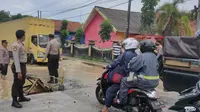 Polisi mengatur lalu lintas akibat banjir luapan sungai Blega Bangkalan. (Dian Kurniawan/Liputan6.com)