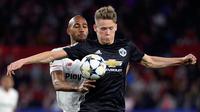 Pemain Manchester United, Scott McTominay berebut bola dengan pemain Sevilla, Steven N'Zonzi pada laga leg pertama 16 besar Liga Champions di Ramon Sanchez Pizjuan, Rabu (21/2). MU pulang dari Sevilla dengan hasil imbang 0-0. (Cristina Quicler/AFP)