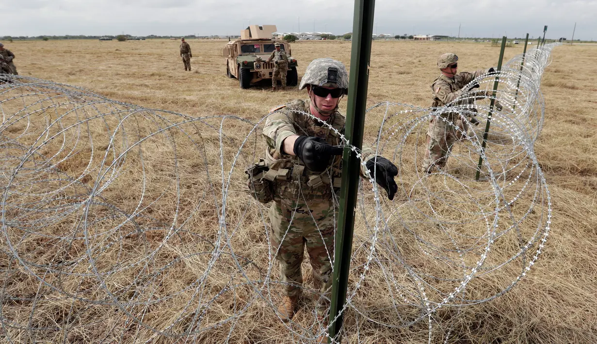 Tentara AS memasang kawat duri dekat jembatan perbatasan antara AS dengan Meksiko di Donna, Texas, Minggu (4/11). Presiden AS Donald Trump mengatakan kehadiran pasukannya untuk mengantisipasi 'invasi' imigran. (AP Photo/Eric Gay)