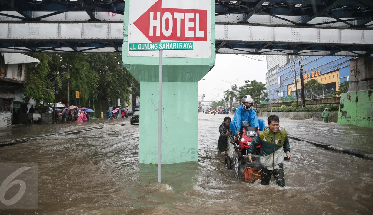 Warga menaiki gerobak untuk menyeberangi banjir yang merendam Jalan Gunung Sahari, Jakarta Pusat, Selasa (21/2). Hujan yang turun sejak dini hari menyebabkan sejumlah ruas jalan terimbas banjir dan tak bisa dilalui kendaraan. (Liputan6.com/Faizal Fanani)
