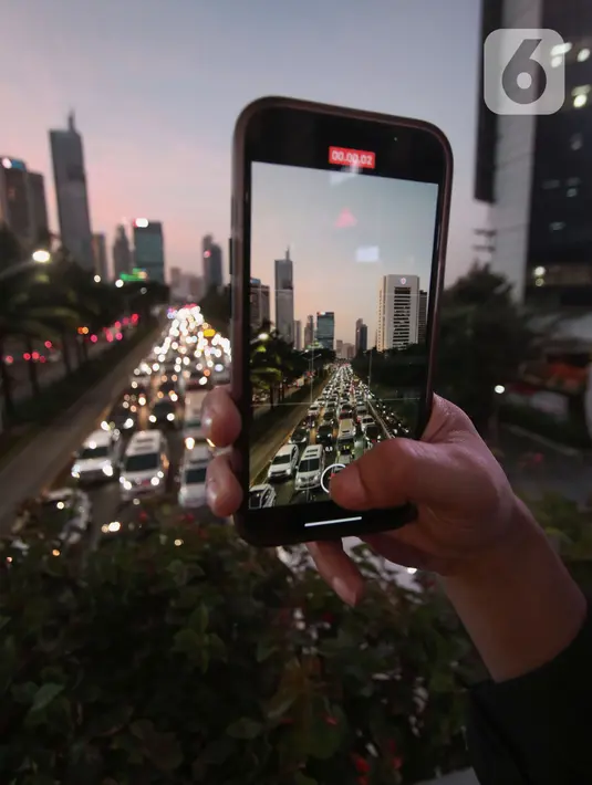 Warga mengambil gambar kendaraan yang terjebak kemacetan panjang dari atas Jembatan Penyeberangan Orang (JPO) di kawasan Sudirman, Jakarta, Rabu (30/8/20230). (Liputan6.com/Angga Yuniar)
