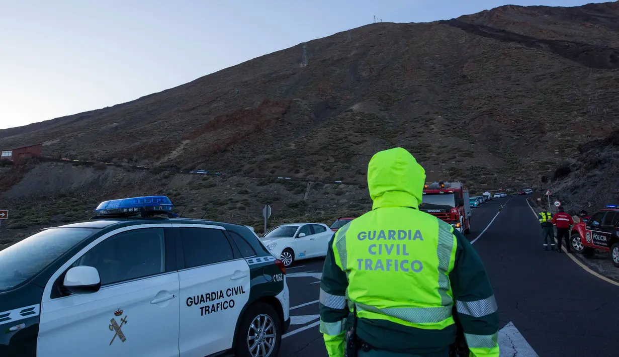 Aparat keamanan berjaga di lereng Gunung El Teide (3.718 meter) di Taman Nasional El Teide, Pulau Canary, Spanyol, Rabu (15/3). Sekitar 60 wisatawan terperangkap di dua kereta gantung saat menuju puncak Gunung El Teide (3.718 meter). (Desiree Martin/AFP)