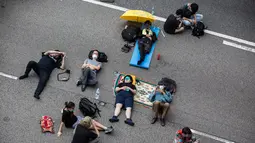 Sejumlah pengunjuk rasa tidur di jalanan saat menggelar protes terkait RUU Ekstradisi di Hong Kong, Senin (17/6/2019). Pengunjuk rasa mengenakan pakaian hitam saat menggelar unjuk rasa menentang RUU Ekstradisi. (ISAAC LAWRENCE/AFP)
