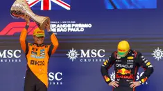 Pembalap Red Bull Racing, Max Verstappen (kanan) tertunduk saat pembalap McLaren, Lando Norrris mengangkat trofi kemenangan dalam Formula 1 GP Sao Paulo di Interlagos, Sao Paulo, Brasil, Minggu (09/11/2025). (AFP/Miguel Schincariol)
