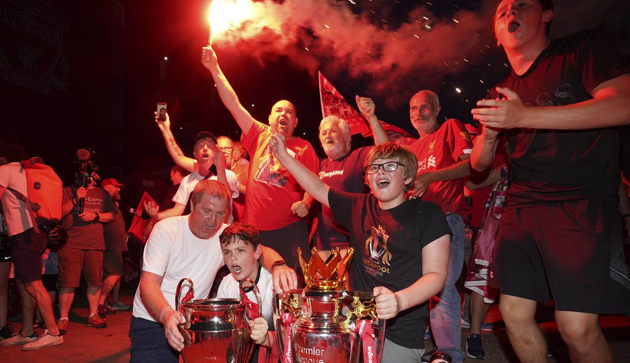 Suporter Liverpool merayakan gelar juara Premier League di depan Stadion Anfield, Kamis (25/6/2020). Titel juara Liga Inggris 2019-20 ini merupakan gelar pertama Liverpool setelah puasa selama 30 tahun. (AP/Jon Super)