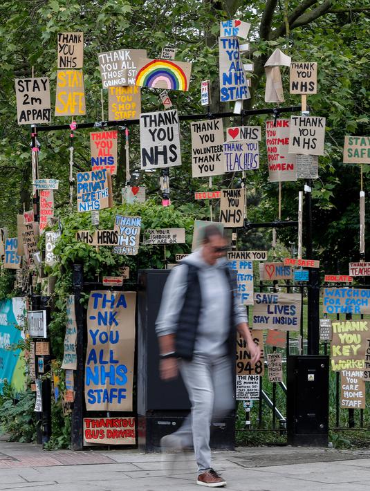 Seorang pria berjalan melewati kumpulan plakat yang dirancang oleh seniman lokal Peter Liversidge untuk mendukung Layanan Kesehatan Nasional (National Health Service/NHS) di London, Inggris, (29/4/2020). (Xinhua/Han Yan)