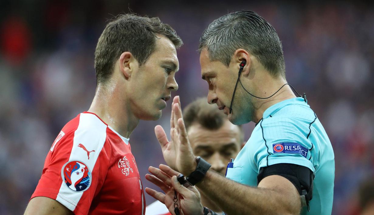 Wasit Damir Skomina memperingatkan pemain Swiss, Stephan Lichtsteiner, pada laga terakhir Grup A Piala Eropa 2016 di Stade Pierre Mauroy, Lille, Senin (20/6/2016) dini hari WIB. (AFP/Kenzo Tribouillard)