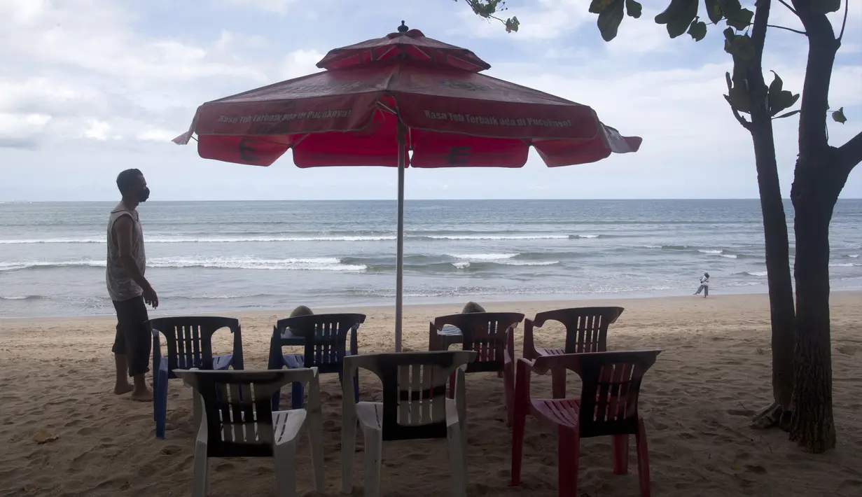 Seorang pedagang menata kursi saat menunggu pelanggan di Pantai Kuta, Bali, Kamis (14/10/2021). Pemerintah mulai membuka penerbangan internasional ke Bali bagi 19 wisatawan mancanegara mulai hari ini. (AP Photo/Firdia Lisnawati)
