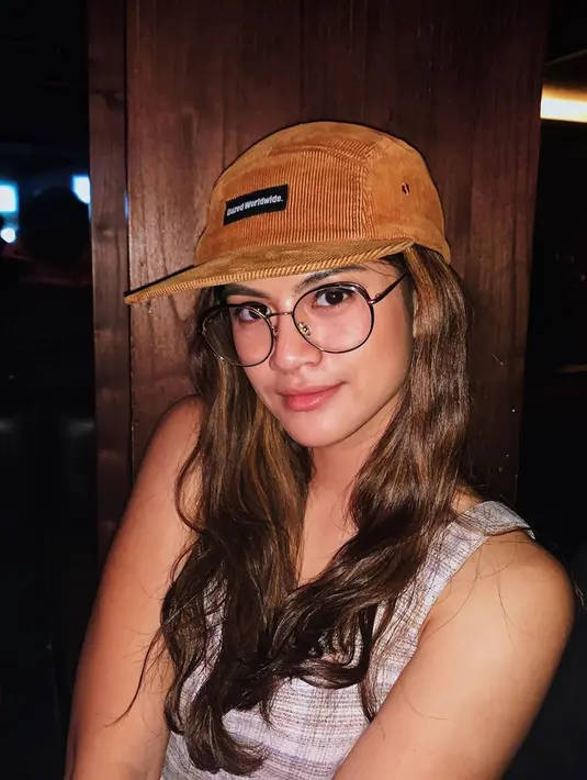 Fashion item kacamata dengan frame besar, membuat penampilan fim '9 Sisi' ini terlihat lebih tirus. Dilengkapi dengan topi baseball, penampilan wanita yang akrab disapa Hana ini semakin edgy dan chic. (Liputan6.com/IG/@hanahaho)