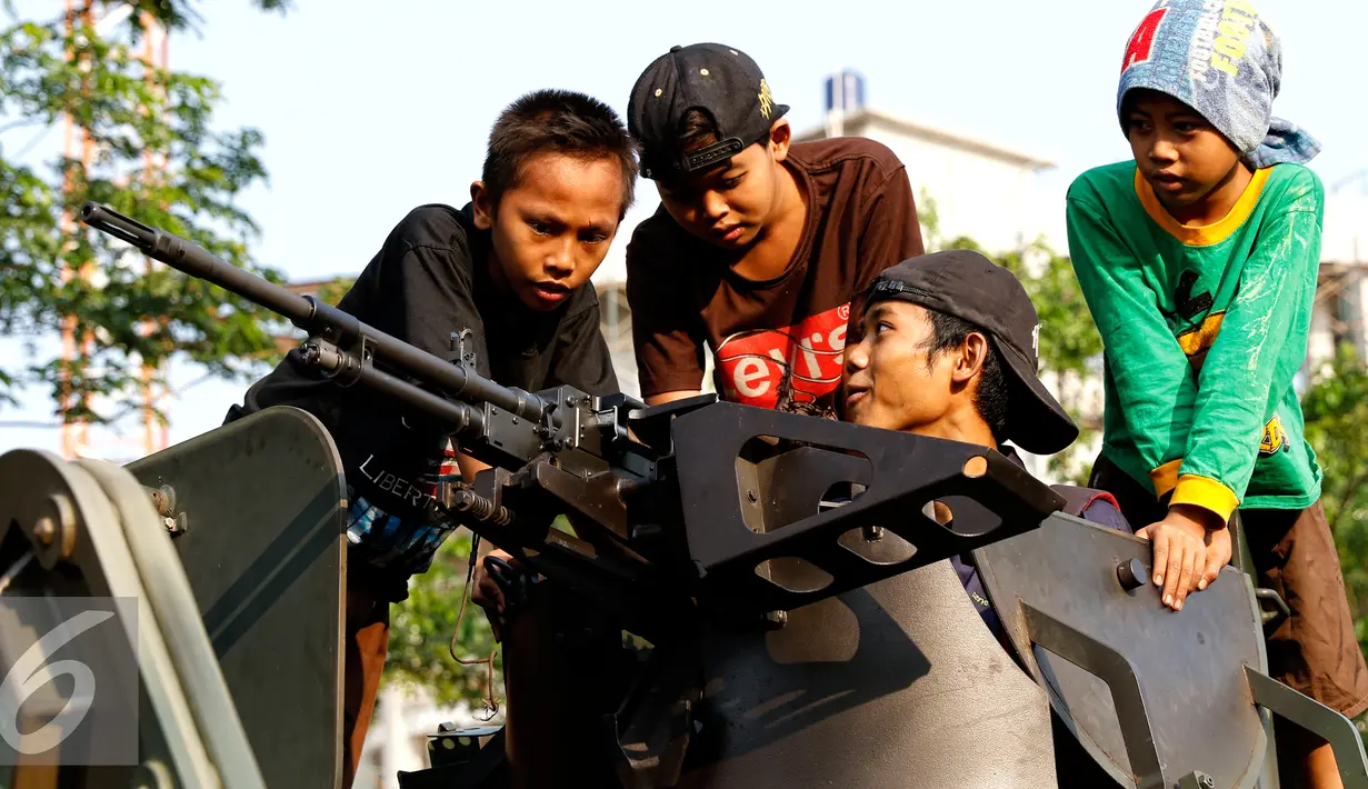 Anak-anak tampak senang memainkan senjata ketika menaiki Panser Anoa dalam pameran road to campus Alat Utama Sistem Persenjataan (Alutsista) di kawasan Boulevard Universitas Indonesia, Depok, Jawa Barat, Kamis (27/8/2015). (Liputan6.com/Yoppy Renato)