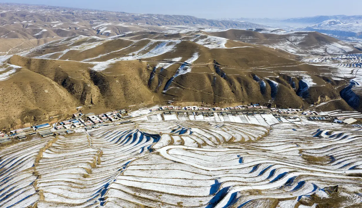 Foto dari udara yang diabadikan pada 7 Desember 2020 ini menunjukkan pemandangan sawah terasering yang tertutup salju di Kota Wuwei, Wilayah Otonom Etnis Tibet Tianzhu, Provinsi Gansu, China barat laut. (Xinhua/Jiang Aiping)