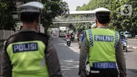 Pengendara sepeda motor melintas saat polisi lalu lintas berjaga pada Operasi Zebra Jaya 2022 di Jakarta, Selasa (4/10/2022). Operasi Zebra Jaya dilaksanakan pada tanggal 3 hingga 17 Oktober untuk menekan jumlah pelanggaran lalu lintas. (Liputan6.com/Faizal Fanani)