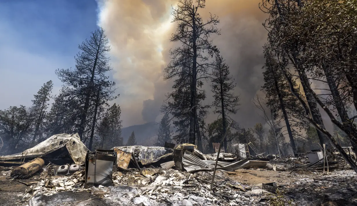 Properti yang hancur tertinggal di belakangnya saat api melahap hutan dekat Midpines, timur laut Mariposa, California (23/7/2022). Api yang bergerak cepat membakar di luar Taman Nasional Yosemite telah memaksa evakuasi, menghanguskan lebih dari 11.500 hektar dan telah menghancurkan beberapa rumah sejak mulai Jumat sore. (AFP/DAVID MCNEW)