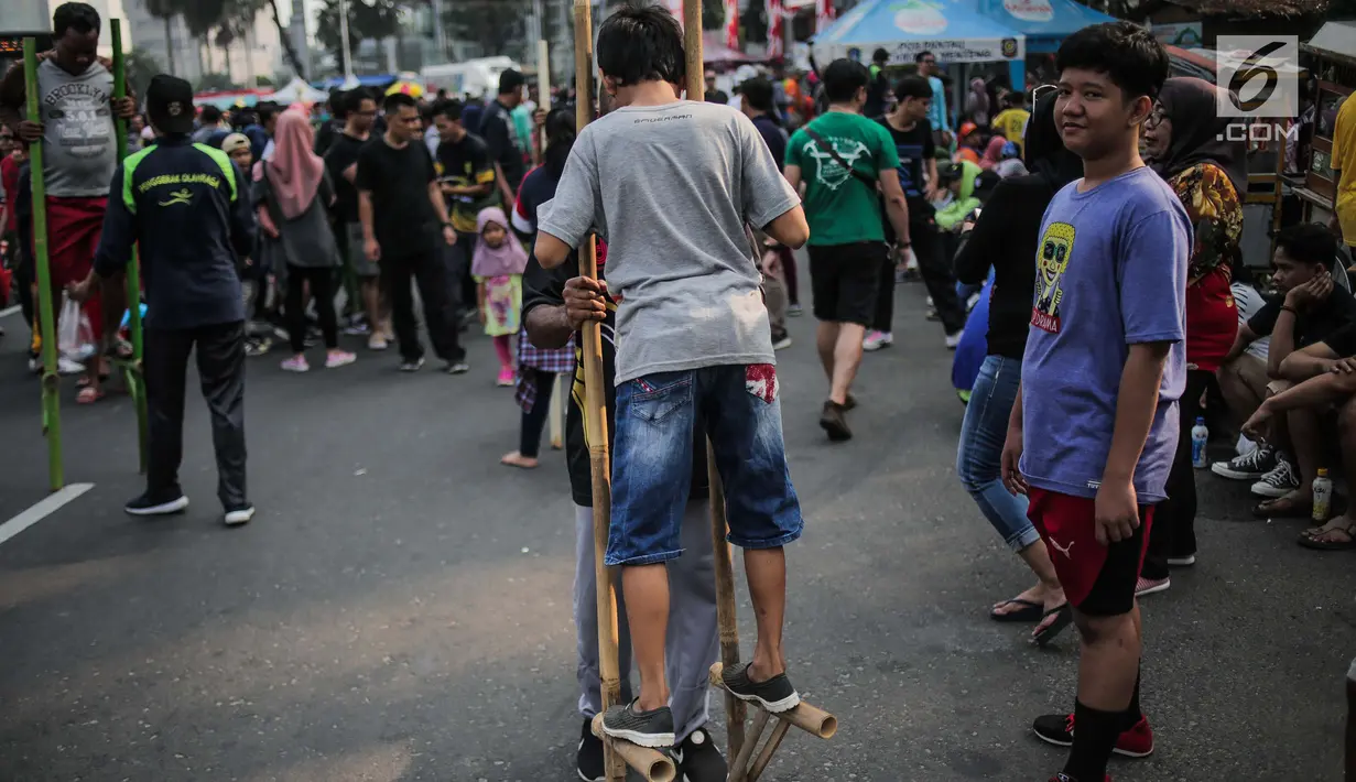 Anak-anak bermain permainan tradisional egrang ditemani sejumlah mahasiswa dari Penggerak Olahraga saat car free day (CFD) di kawasan Bundaran HI, Jakarta, Minggu (14/7/2019). Kegiatan yang rutin digelar ini bertujuan mengajak masyarakat DKI Jakarta aktif berolahraga. (Liputan6.com/Faizal Fanani)