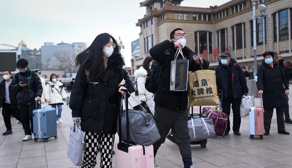 Penumpang membawa tas mereka ke pintu masuk stasiun kereta api Beijing di ibu kota China (7/1/2023). Ketika migrasi tahunan dimulai dengan orang-orang yang kembali ke kampung halaman mereka untuk perayaan Tahun Baru Imlek. (AFP/Wang Zhao)