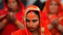 Ekspresi seorang wanita Nepal yang mengenakan bubuk vermilion saat melakukan doa di tepi Sungai Bagmati selama festival Chhath Puja di Kathmandu, Nepal (26/10). Acara ini merupakan ritual Hindu kuno. (AP Photo/Niranjan Shrestha)