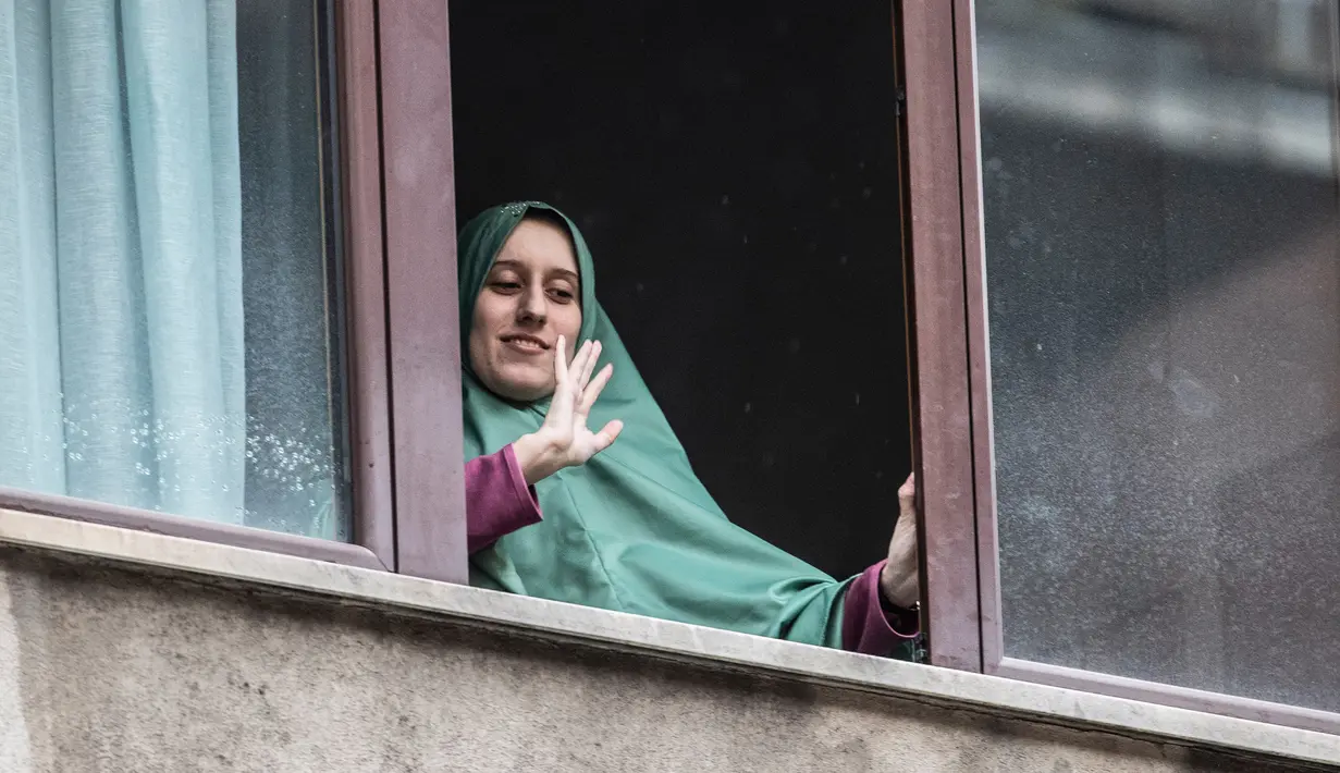 Petugas bantuan Italia Silvia Romano, yang dibebaskan oleh militan Somalia, terlihat di jendela setelah tiba di rumahnya di Milan, 11 Mei 2020. Silvia, 25 tahun, mengakui alasan dia memeluk Islam bukan karena pernikahan atau menjalin hubungan dengan pria mana pun. (AP/Luca Bruno)