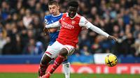 Gelandang Arsenal, Bukayo Saka, mendapatkan pengawalan dari bek Everton, Vitaliy Mykolenko, pada pertandingan pekan ke-22 Premier League 2022/2023 yang digelar di Goodison Park, Sabtu (4/2/2023) malam WIB. (AFP/Paul Ellis)