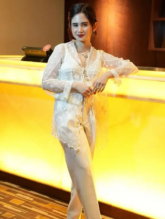 Tissa Biani tampil kasual mengenakan kebaya modern putih transparan dipadukan inner kutang warna senada serta celana panjang warna beigenya. [@tissabiani]