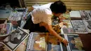 Seorang pedagang merapikan koran-koran jualannya yang memberitakan wafatnya Raja Thailand Bhumibol Adulyadej, di Bangkok, Jumat (14/10). Raja Bhumibol meninggal di usia 88 tahun dan wajahnya menghiasi berbagai media cetak di Thailand. (Reuters/Edgar Su)
