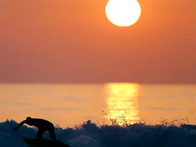 Seorang pria berselancar saat matahari terbenam di sebuah pantai di La Serena, Chile, Selasa (23/5/2015). (REUTERS/Marcos Brindicci)