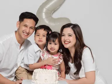 Anak keduanya genap berusia dua tahun, kebahagiaan terpancar jelas di wajah Tasya Kamila dan Randi Bachtiar. Tasya Kamila, Randi, dan si sulung Arassya selaras mengenakan busana putih, sementara Shafanina mengenakan dress simpel floral warna merah muda. Rambut gadis kecil yang akrab disapan Shanin itu dikepang dua sehingga membuatnya terlihat menggemaskan. (Liputan6.com/IG/@tasyakamila)