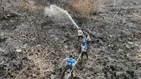 Pendinginan kebakaran lahan di perbatasan Kota Dumai dengan Kabupaten Bengkalis. (Liputan6.com/M Syukur)