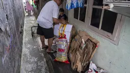 Seorang pria menyiapkan sampah rumah tangga anorganik, berupa kardus dan botol plastik, untuk disetorkan ke bank sampah setempat, Jakarta, Kamis 4 Juni 2026, sebagai bagian dari instruksi Pemprov DKI yang mewajibkan warga memilih dan memilah sampah untuk mengurangi beban sampah yang semakin menumpuk di ibu kota. (BAY ISMOYO/AFP)