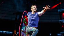 Aksi vokalis band Inggris Coldplay, Chris Martin saat tampil di The Stade de France Arena di Saint Denis, Paris, Prancis (15/7). (AFP Photo/Geoffroy Van Der Hasselt)