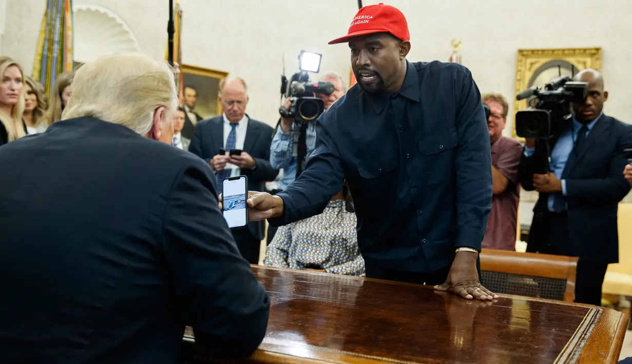 Rapper Kanye West menunjukkan foto pesawat hidrogen kepada Presiden AS, Donald Trump selama pertemuan di Oval Office, Gedung Putih, Kamis (11/10). West diundang untuk makan siang guna membahas reformasi penjara dan masalah lainnya. (AP/Evan Vucci)