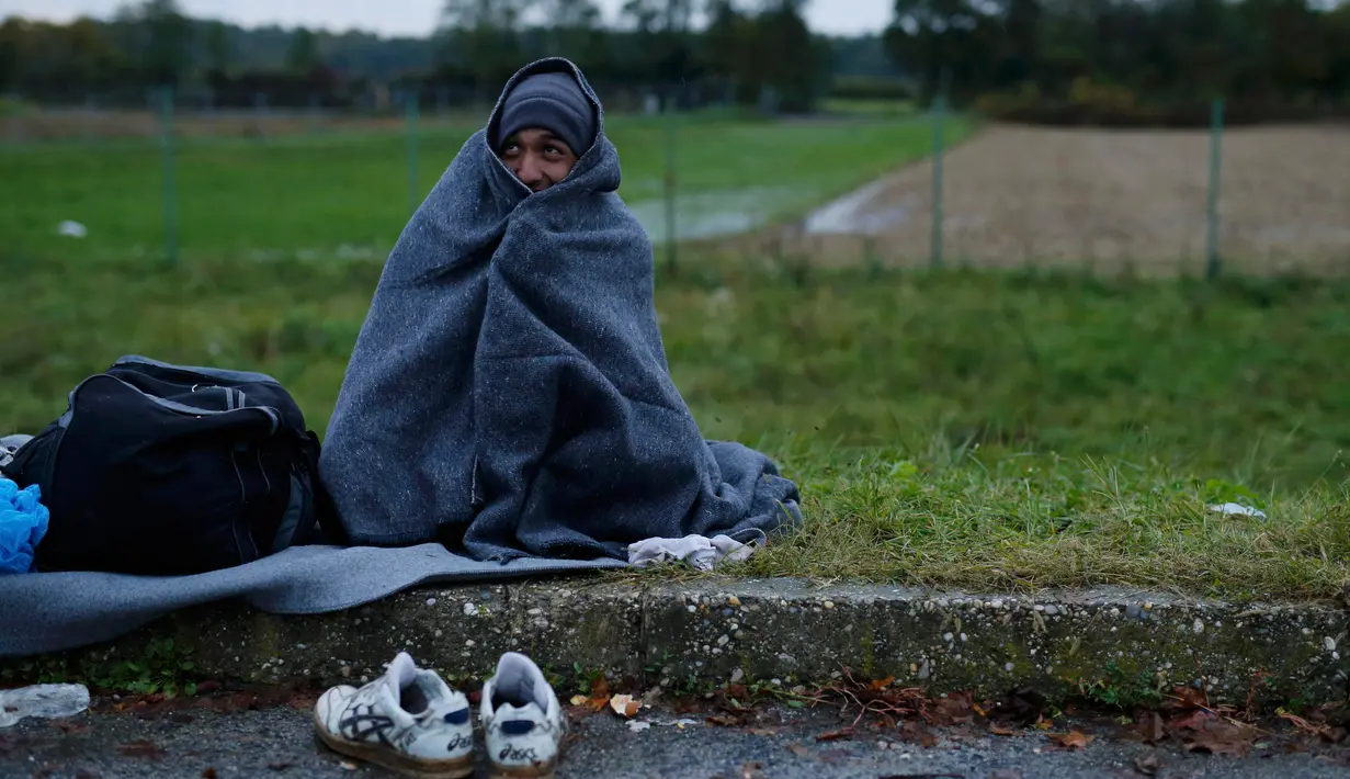 Pengungsi terbungkus selimut saat menunggu menyeberang perbatasan dari Slovenia menuju Trnovec, Kroasia, Senin (19/10). Ribuan orang terjebak cuaca dingin di desa perbatasan Serbia Berkasovo usai Kroasia membendung para pendatang. (REUTERS/Antonio Bronic)