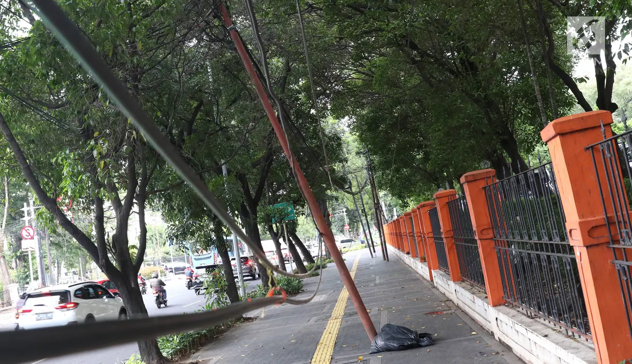 Kondisi tiang yang miring di Jalan Gedung Kesenian, Jakarta, Jumat (22/2). Keberadaan tiang miring tersebut membahayakan keselamatan pejalan kaki karena kabel yang turut menjuntai hingga ke bawah. (Liputan6.com/Immanuel Antonius)