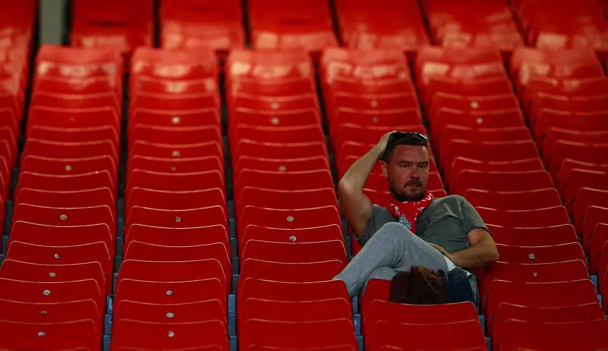 Fans Liverpool duduk sambil memegang kepalanya usai pertandingan melawan Wolverhampton Wanderers pada lanjutan Liga Inggris di stadion Anfield (12/5/2019). Meskipun menang 2-0, Liverpool gagal meraih juara Liga Inggris karena Manchester City mengalahkan Brighton 4-1. (AP Photo/Dave Thompson)