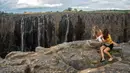 Wisatawan menikmati air terjun Victoria, salah satu air terjun terbesar di dunia, di Zimbabwe pada 10 Desember 2019. Musim kemarau yang terjadi membuat air terjun yang masuk dalam Situs Warisan Dunia UNESCO ini mengalami kekeringan terparah selama beberapa dekade lalu. (ZINYANGE AUNTONY/AFP)