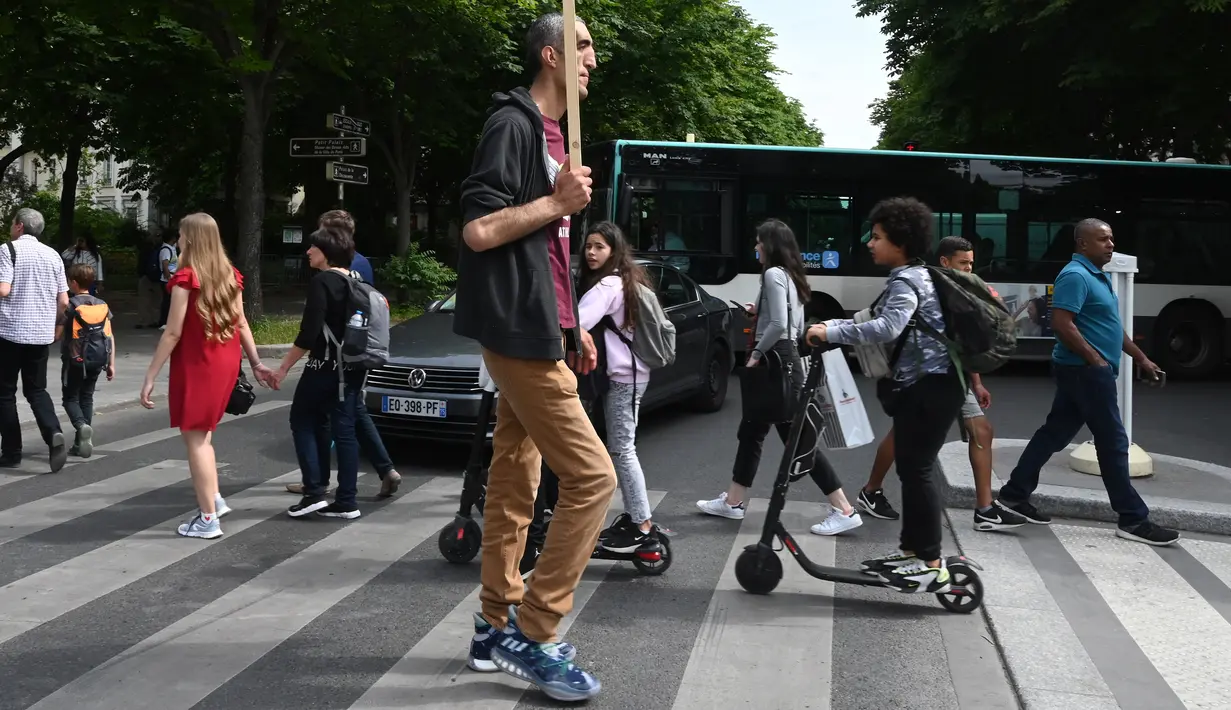 Arshavir Grigoryan yang memiliki tinggi tubuh 2 meter 33 centimeter berjalan saat berkumpul di Champs-Elysees Avenue di Paris, Prancis (14/6/2019). Sambil membawa poster, belasan pria tertinggi dunia berkumpul pada akhir pekan di Champs-Elysees Avenue. (AFP Photo/Dominique Faget)