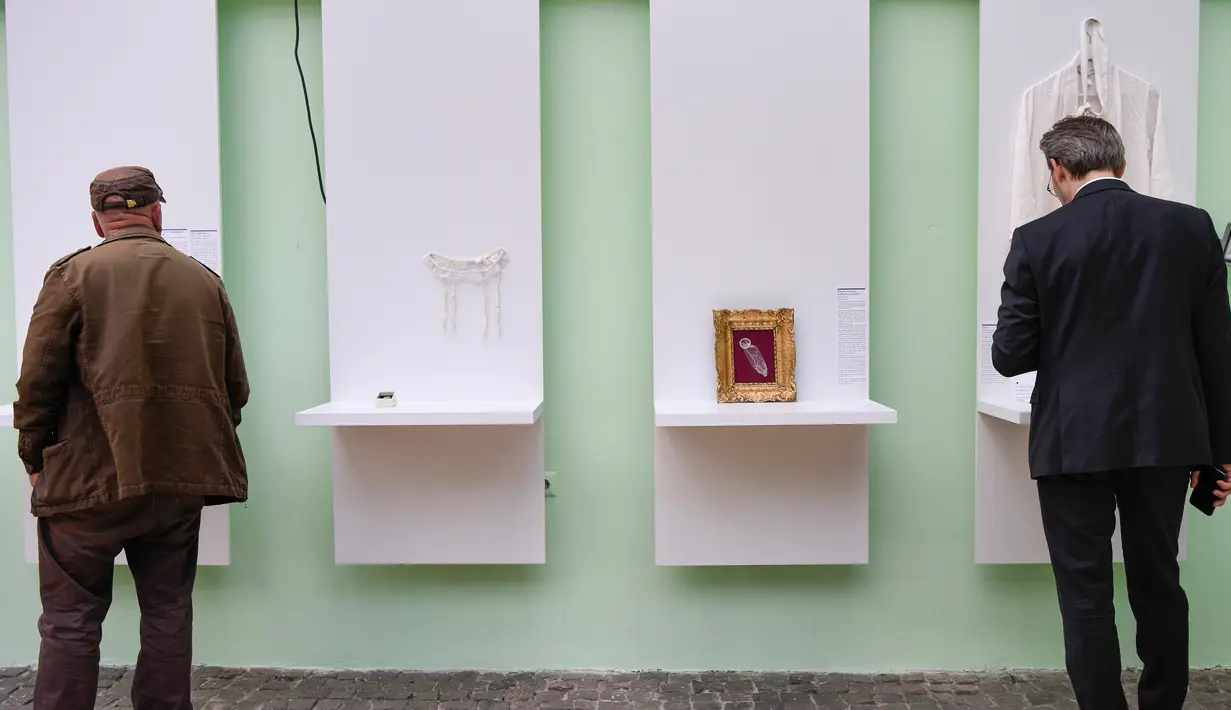 Pengunjung melihat koleksi barang-barang yang dipamerkan dalam pembukaan Museum of Broken Relationships di Kosovo, Kamis (3/5). Masing-masing benda disertai dengan kartu yang berisi kata-kata dari penyumbangnya. (ARMEND NIMANI/AFP)