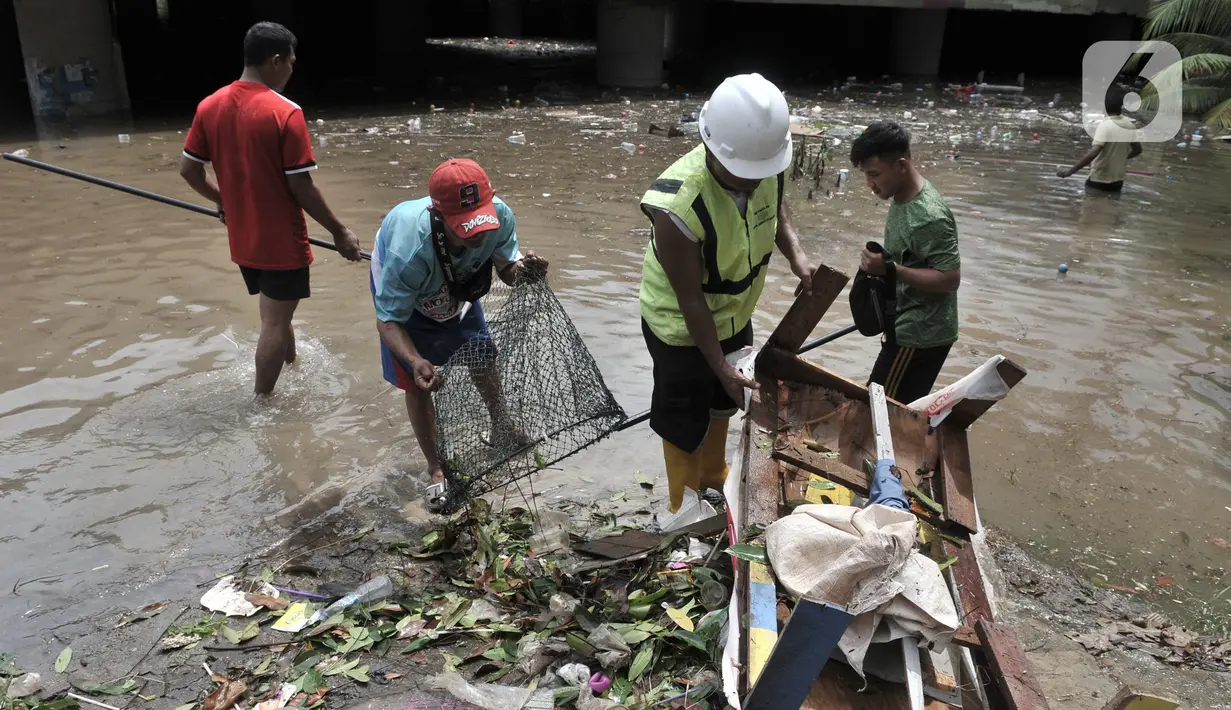 Petugas Pusat Pengelolaan Kompleks (PPK) Kemayoran membersihkan sampah yang muncul akibat banjir di Underpass Kemayoran, Jakarta, Minggu (2/2/2020). Selain melumpuhkan akses, banjir setinggi hingga 5 meter tersebut menyebabkan sampah memenuhi Underpass Kemayoran. (merdeka.com/Iqbal S. Nugroho)