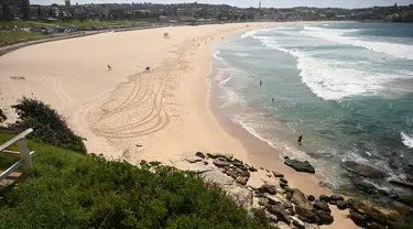 Pantai Bondi yang kosong setelah pemerintah menutup pantai paling populer di Sydney, Minggu (22/3/2020). Otoritas Australia menutup Bondi Beach  lantaran orang-orang mengabaikan larangan pemerintah untuk tidak berkumpul dalam jumlah besar guna menekan penyebaran virus corona. (PETER PARKS/AFP)