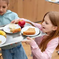 Ilustrasi dua anak perempuan yang sedang mengambil makan siang gratis di sekolahnya (Foto dok : Freepik/freepik).