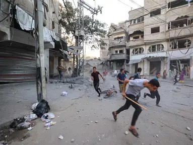 Orang-orang berlari mencari perlindungan setelah serangan Israel yang menargetkan sebuah bangunan di kamp pengungsi Palestina Bureij di Jalur Gaza tengah pada 19 Oktober 2025. (Eyad BABA/AFP)