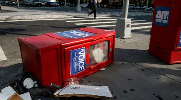 Sebuah kotak surat kabar Village Voice tergeletak di samping tempat sampah di Manhattan, AS (22/8). Village Voice  adalah surat kabar mingguan tertua dan paling terkenal di AS. (Drew Angerer/Getty Images/AFP)