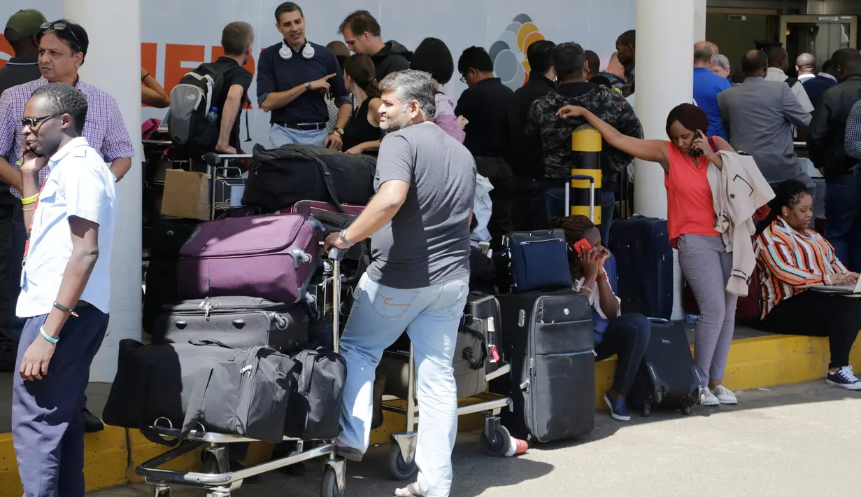 Penumpang yang terdampar menunggu penerbangan mereka di bandara JKIA, Nairobi, Rabu (6/3). Aksi mogok dipicu dengan rencana penyerahan manajemen bandara terbesar di Kenya kepada maskapai nasional yang merugi. (AP Photo/Khalil Senosi)