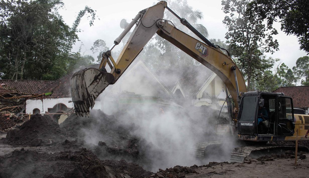 Sebelumnya, material vulkanik Gunung Semeru, yang mengalami erupsi pada Rabu, 19 November 2025, menerjang Desa Supiturang, Kecamatan Pronojiwo, Kabupaten Lumajang, Jawa Timur. Tampak dalam foto, alat berat membersihkan abu di depan sebuah rumah yang hancur akibat aliran piroklastik Gunung Semeru di Desa Supiturang, Lumajang, Jawa Timur, pada Jumat 21 November 2025. (Agus Harianto/AFP)