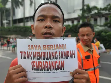 Seorang warga menunjukkan tulisan "Saya Berjanji Tidak Membuang Sampah Sembarangan" saat menjalani sidang karena tertangkap membuang sampah sembarangan di kawasan Bundaran HI, Jakarta, Minggu (24/4).(Liputan6.com/ Gempur M Surya)