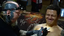 Pengunjung terlihat kesakitan saat ditato oleh seniman Paul Booth di edisi 5 Konvensi Internasional Paradise Tatto, di San Antonio de Belen, San Jose, (8/5). Lebih dari 300 seniman tato berpartisipasi di acara ini.(AFP PHOTO/Ezequiel Becerra)
