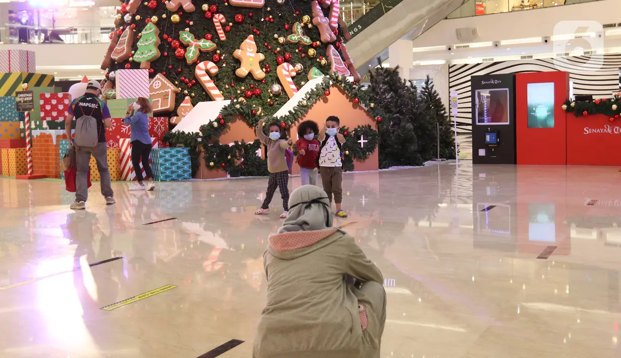 Anak-anak berpose di depan pohon Natal di Senayan City, Jakarta, Senin (21/12/2020). Senayan City menghadirkan Classic Christmas tree setinggi 18 meter yang dipenuhi dengan hiasan ornamen khas Natal manusia salju serta candy cane. (Liputan6.com/Herman Zakharia)